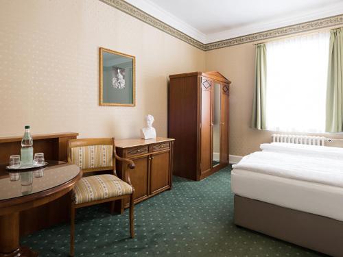 a hotel room with a bed and a desk and a table at Boutique-Hotel Amalienhof in Weimar