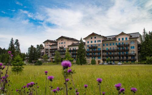 a field of flowers in front of a large building at Residence Grand Hotel Carezza in Nova Levante