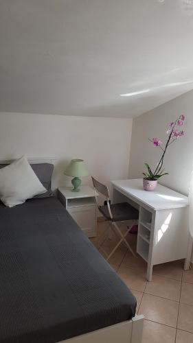 ein Schlafzimmer mit einem Bett und einem Schreibtisch mit einer Blume in der Unterkunft Guest House in Palazzo San Gervasio