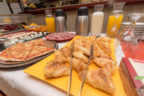 a table with pizzas and pizzas on skewers on at Hotel Lirak in Tetovo