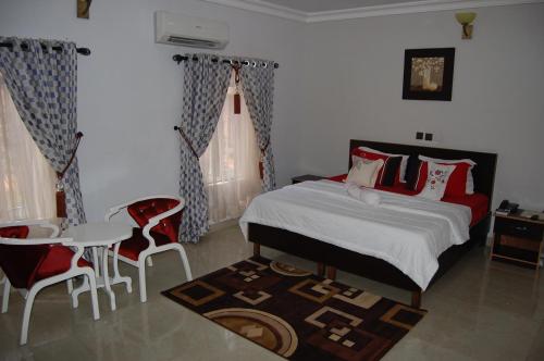 a bedroom with a bed and a table and chairs at Nue-Crest Hotels & Suites in Enugu