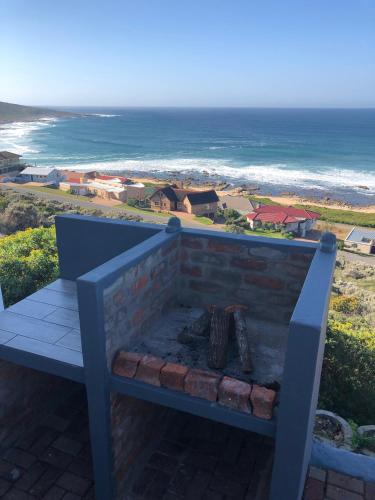 a bench with a fireplace with the ocean in the background at Captain Sunshine Guest House in Jongensfontein