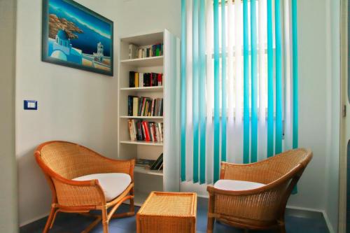 a room with two chairs and a book shelf at Villa Doris in Fontane Bianche