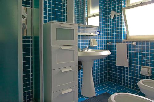 a blue tiled bathroom with a sink and a toilet at Villa Doris in Fontane Bianche