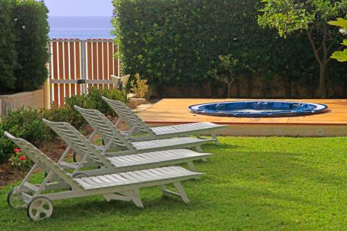 a row of lounge chairs in a yard with a pool at Villa Doris in Fontane Bianche