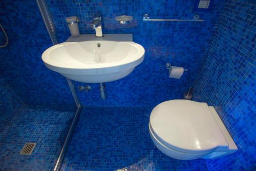 a blue bathroom with a toilet and a sink at Villa Doris in Fontane Bianche