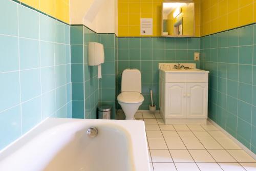 a bathroom with a tub and a toilet at Flandria Hotel in Ghent