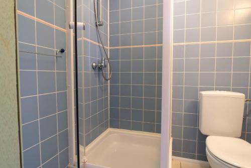 a bathroom with a toilet and a shower with blue tiles at Flandria Hotel in Ghent