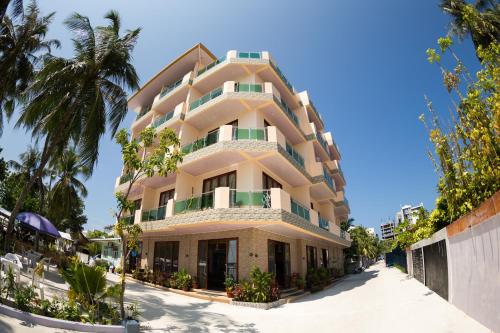a large building with balconies and palm trees at Sunrise Beach in Maafushi