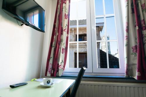 a table with a cup of coffee and a window at Flandria Hotel in Ghent