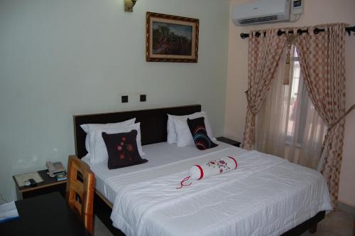 a bedroom with a bed with white sheets and pillows at Nue-Crest Hotels & Suites in Enugu