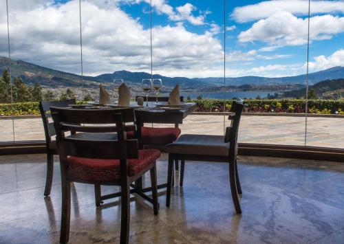 a dining room table with chairs and a view of the water at Hotel Medina Del Lago in Otavalo