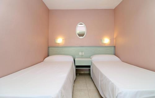 2 bedden in een kleine kamer met een spiegel bij Bermudas 314 in Benidorm
