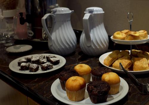 a table topped with plates of muffins and cupcakes at Hotel UOM Buenos Aires in Buenos Aires