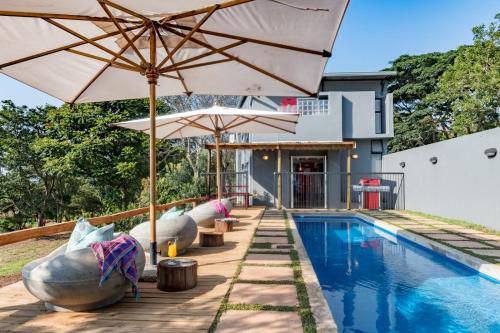 an umbrella and chairs next to a swimming pool at Bluemere Living in White River