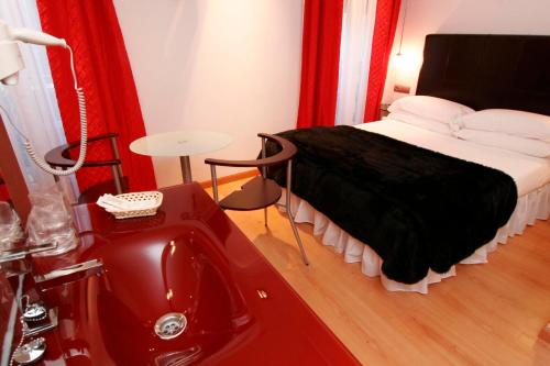 a bedroom with a bed with a sink and a red tub at Hostal Santo Domingo in Madrid
