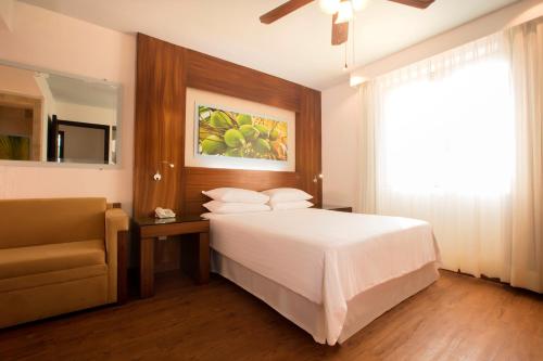 a bedroom with a bed and a chair and a window at Krystal Grand Nuevo Vallarta in Nuevo Vallarta 