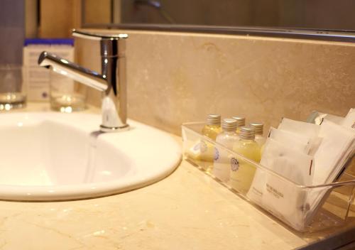 a bathroom counter with a sink and bottles of soap at Hotel UOM Buenos Aires in Buenos Aires