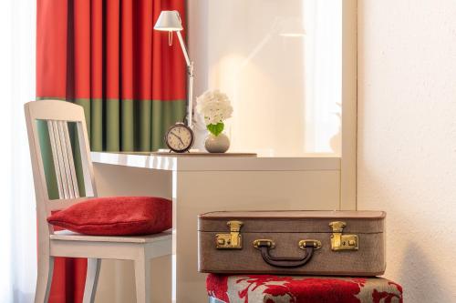 a table with a desk with a suitcase on a chair at Weinstadt Hotel - das Original in Weinstadt