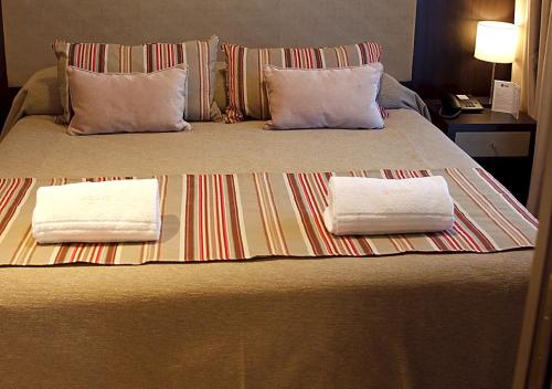 a bed with two pillows and two towels on it at Hotel UOM Buenos Aires in Buenos Aires