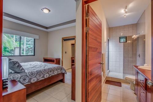 a bedroom with a bed and a bathroom at Hidden Palms in Nosara