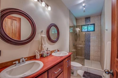 a bathroom with two sinks and a toilet and a shower at Hidden Palms in Nosara