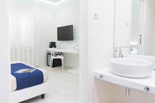 a white bathroom with a sink and a desk at Hotel L'Aragosta in La Caletta