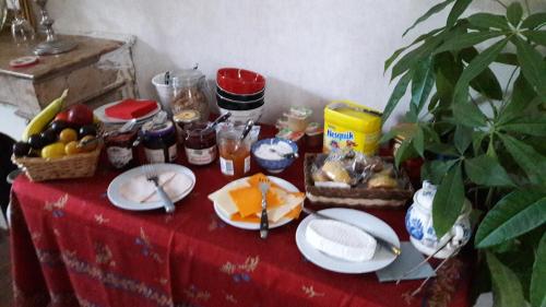 a table with a red table cloth with food on it at Le petit plessis in Ruaudin