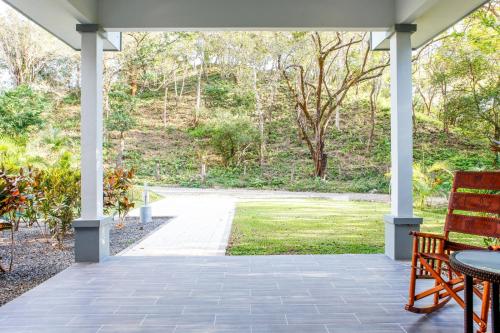 a porch with a table and a bench and a view at Hidden Palms in Nosara