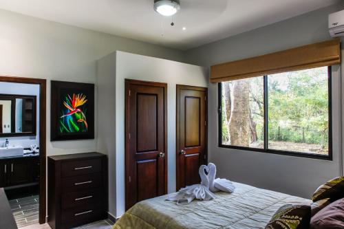 a bedroom with a bed with a dresser and a window at Hidden Palms in Nosara