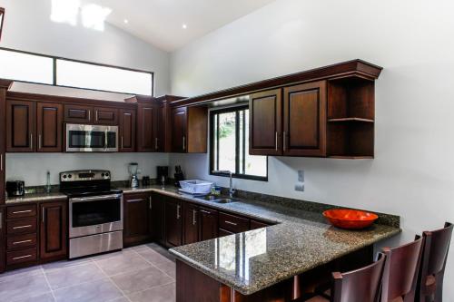 a kitchen with wooden cabinets and a counter top at Hidden Palms in Nosara