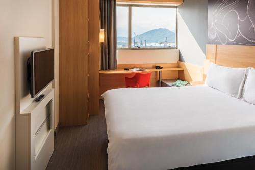 a hotel room with a bed and a television at ibis Santos Valongo in Santos