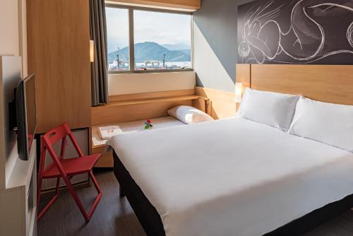 a hotel room with a bed and a red chair at ibis Santos Valongo in Santos
