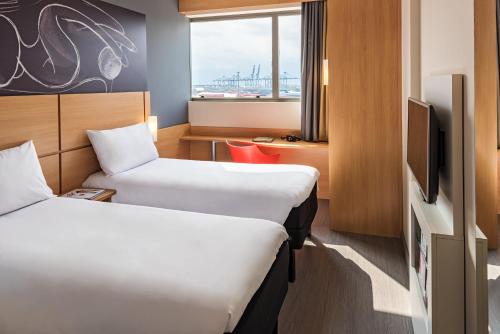a hotel room with two beds and a tv at ibis Santos Valongo in Santos
