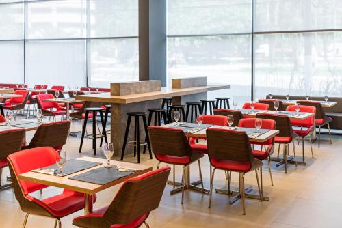 a restaurant with red chairs and tables and windows at ibis Santos Valongo in Santos