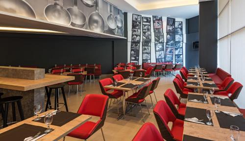 a restaurant with wooden tables and red chairs at ibis Santos Valongo in Santos