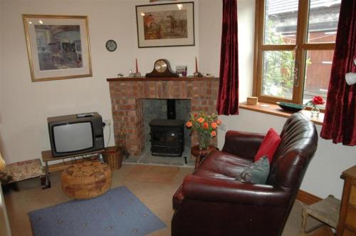 sala de estar con sofá de cuero y chimenea en Neuadd Arms Hotel en Llanwrtyd Wells