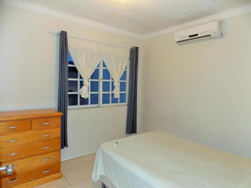 1 dormitorio con 1 cama, vestidor y ventana en 02 - CASA praia PINHEIRA pousada, en Palhoça