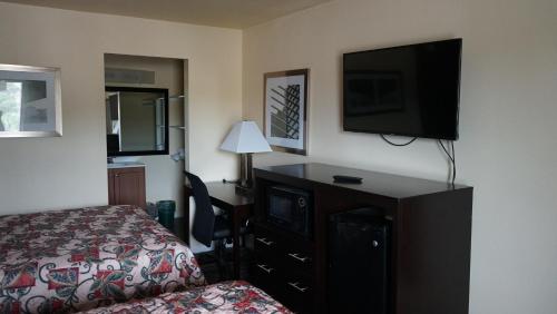 a hotel room with a bed and a desk with a television at Village Motor Inn in Austin