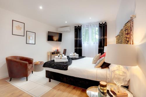 a bedroom with a king sized bed and a chair at La Villa Des Sens in Lattes