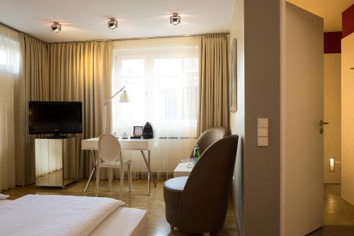 a hotel room with a bed and a desk with chairs at Hotel Santo in Cologne