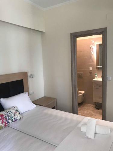 a bedroom with a white bed and a bathroom at Stami's Seaside Apartment in Pyrgi