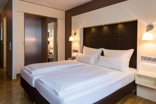 a bedroom with a large bed with white pillows at Hotel Santo in Cologne
