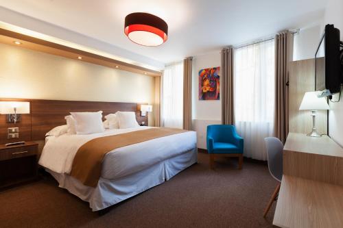 a hotel room with a large bed and a blue chair at Inti Punku Machupicchu Hotel & Suites in Machu Picchu