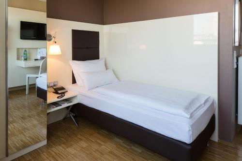 a bedroom with a bed and a desk with a television at Hotel Santo in Cologne