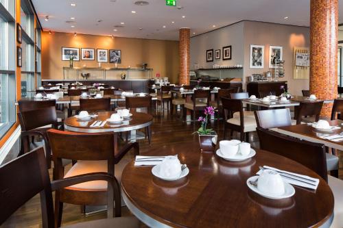 un restaurant avec des tables et des chaises en bois et une salle à manger dans l'établissement Hotel Santo, à Cologne