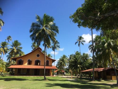 a house with palm trees in front of it at Pousada Igrejinha dos Carneiros in Tamandaré