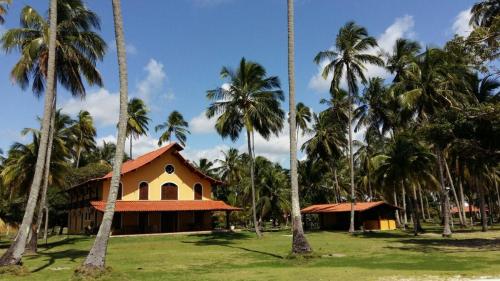 a building with palm trees in front of it at Pousada Igrejinha dos Carneiros in Tamandaré
