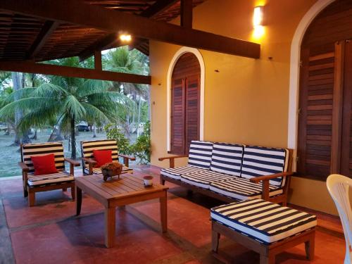 a porch with three benches and a table and chairs at Pousada Igrejinha dos Carneiros in Tamandaré