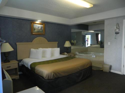 a hotel room with a bed and a bath tub at Village Inn & Suites - Smithville in Smithville